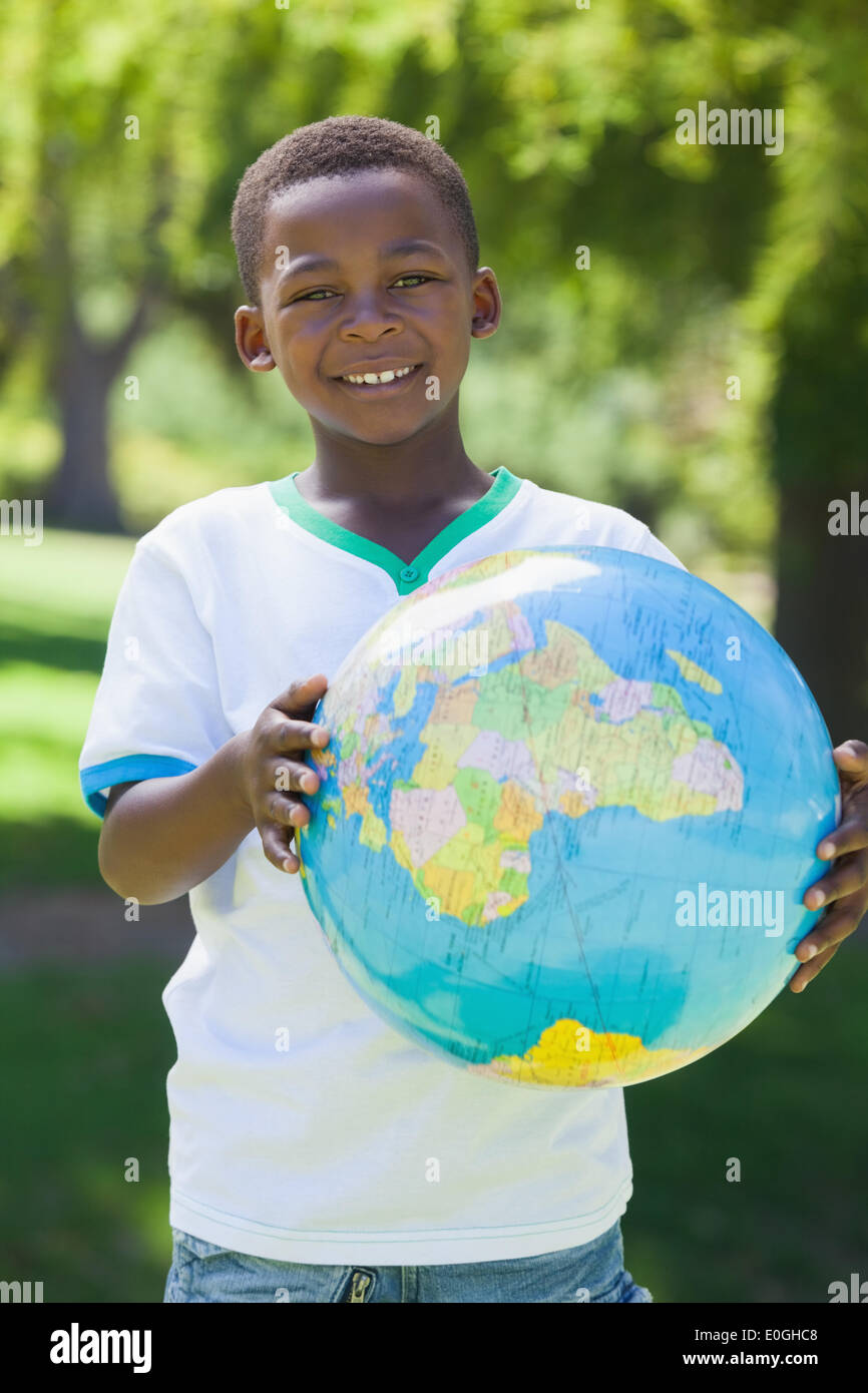 Little boy smiling at camera holding globe in the park Stock Photo