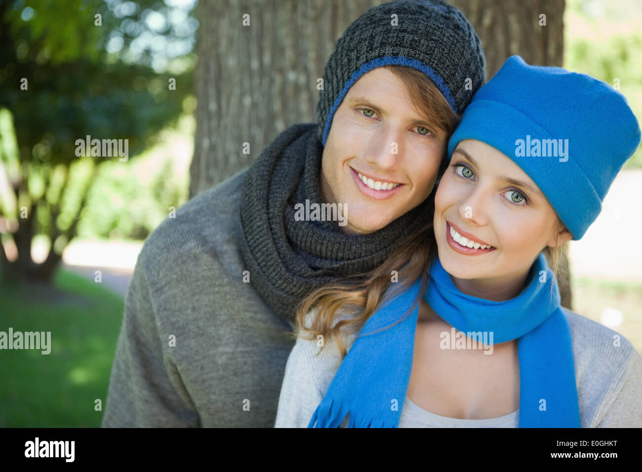 Cute couple smiling at camera in hats and scarves Stock Photo