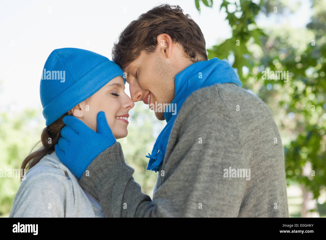 Cute couple standing in the park in hats and scarves Stock Photo