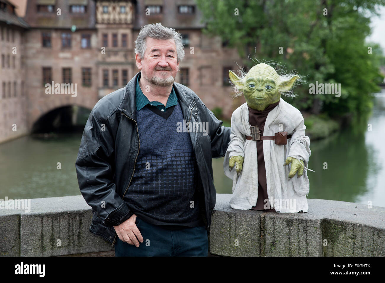 Nuremberg, Germany. 07th May, 2014. Make-up artist Nick Maley, one of the designers of Yoda from the science fiction film Star Wars stands with a Yoga figure at the old town in Nuremberg, Germany, 07 May 2014. 64 year-old is planning a new museum for special effects, fantasy and science fiction films in Nuremberg. Photo: DANIEL KARMANN/dpa/Alamy Live News Stock Photo