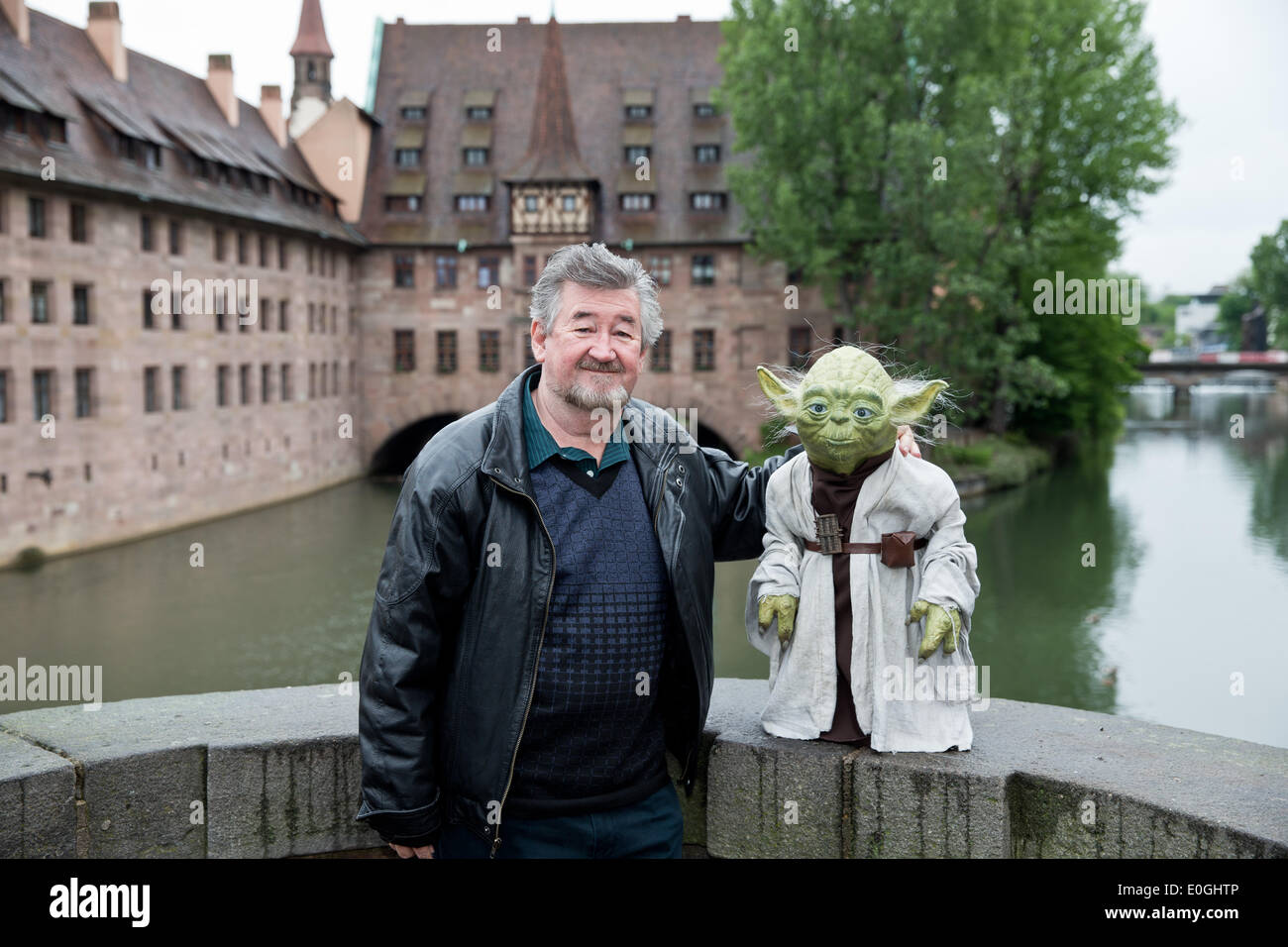 Nuremberg, Germany. 07th May, 2014. Make-up artist Nick Maley, one of the designers of Yoda from the science fiction film Star Wars stands with a Yoga figure at the old town in Nuremberg, Germany, 07 May 2014. 64 year-old is planning a new museum for special effects, fantasy and science fiction films in Nuremberg. Photo: DANIEL KARMANN/dpa/Alamy Live News Stock Photo