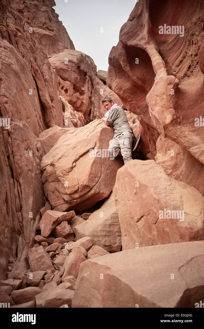Young man on a rock, demanding hike circumnavigation of the Seven Pillars of Wisdom mountain, Wadi Rum, Jordan, Middle East, Asi Stock Photo