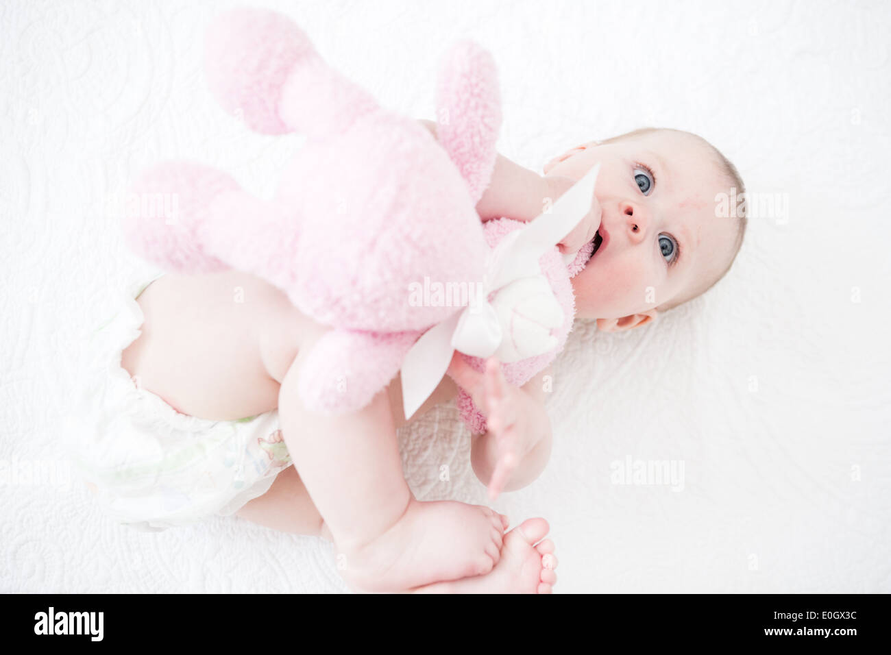 Cute baby girl playing on a white blanket Stock Photo - Alamy