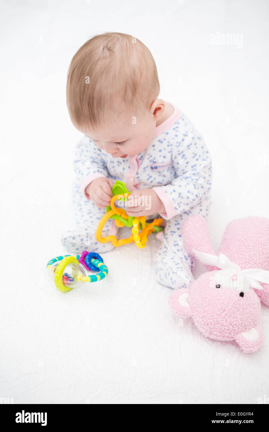 Cute baby girl playing on a white blanket Stock Photo - Alamy