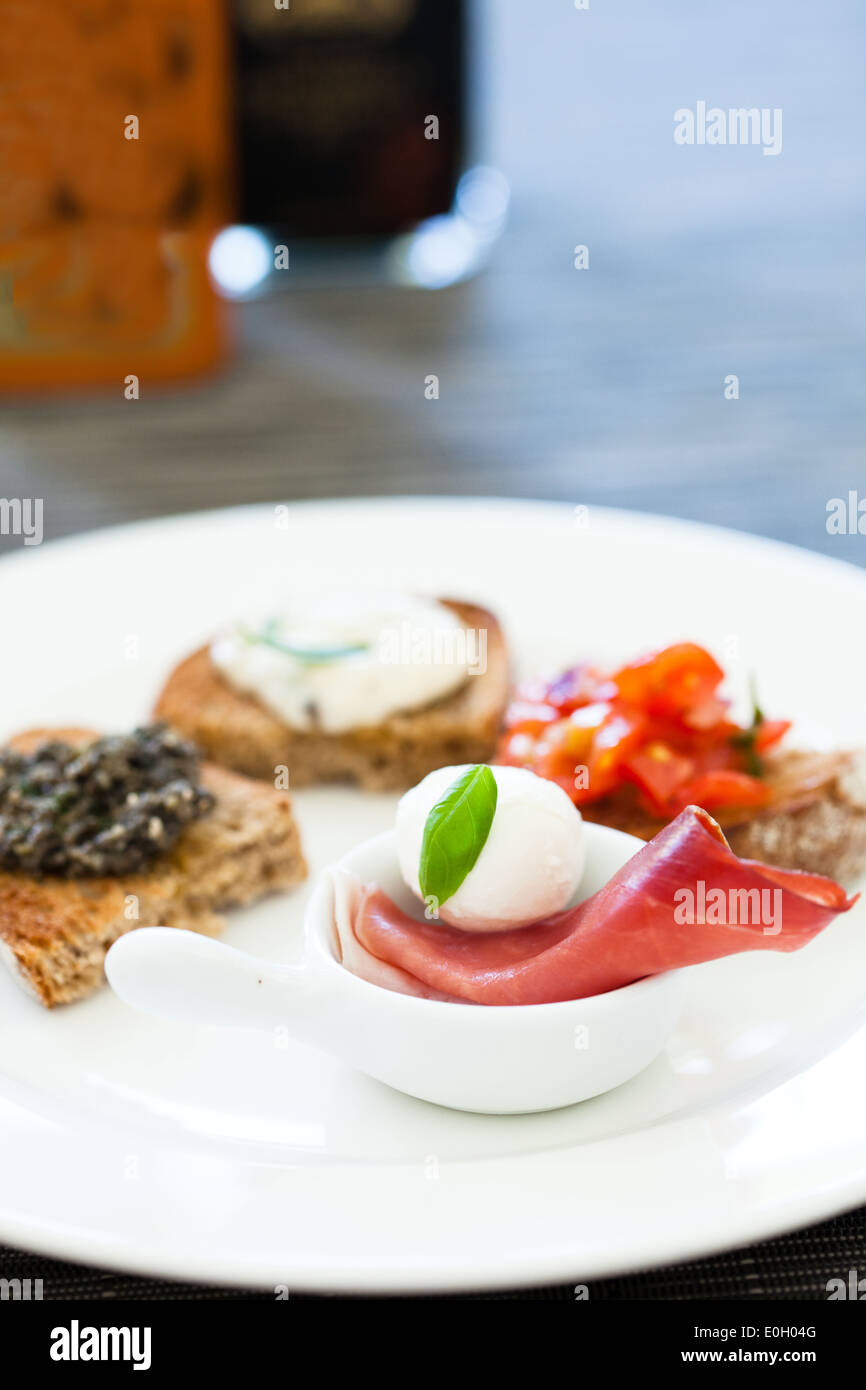 Closeup of plate of appetizers with prosciutto ham and mozzarella