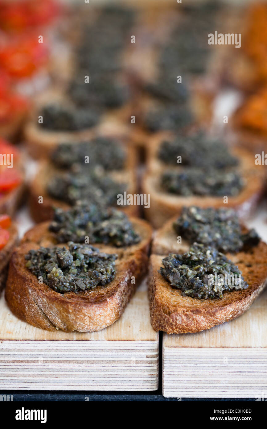 Closeup of bruschetta appetizers with savoury paste topping presented in rows Stock Photo
