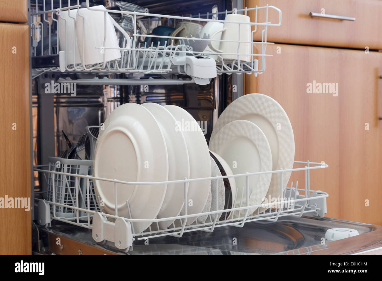 Open fitted dishwasher with clean washed dishes in a kitchen. UK, Britain Stock Photo