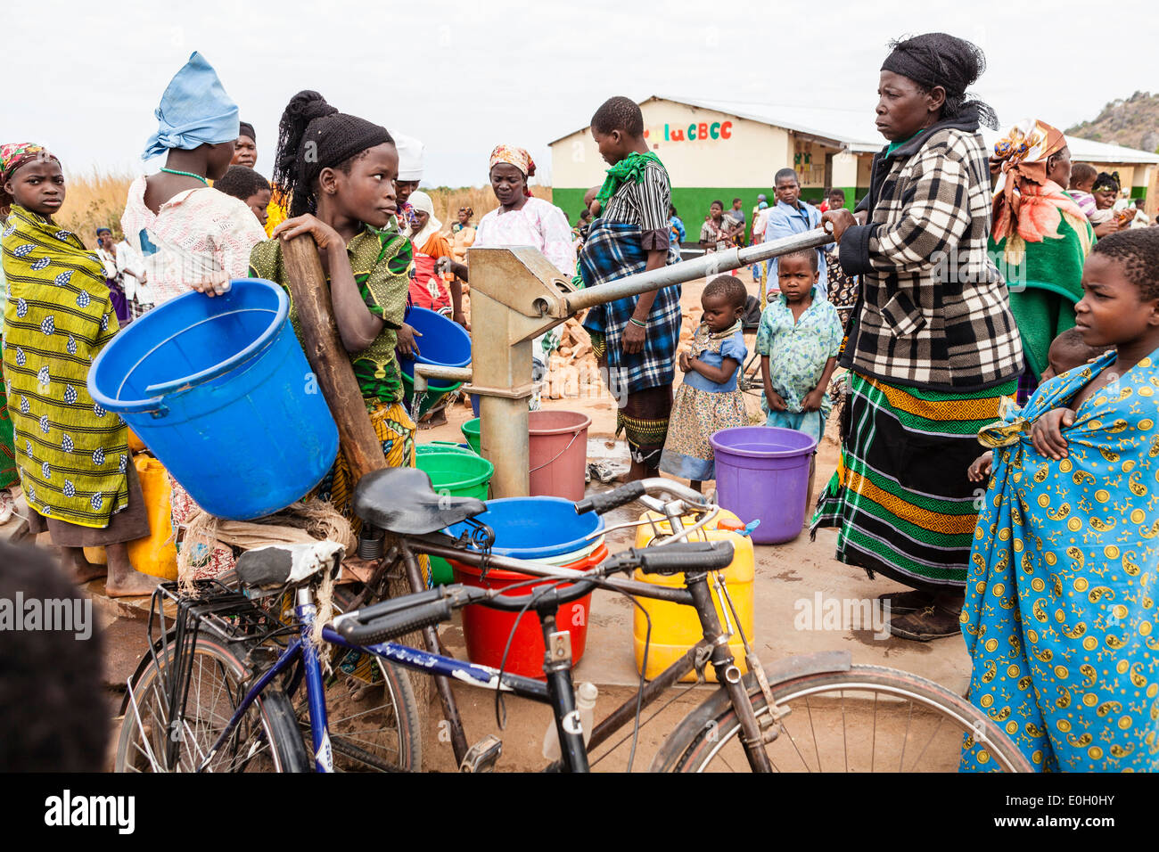 Women at the water well, pump in front of a school in the village of