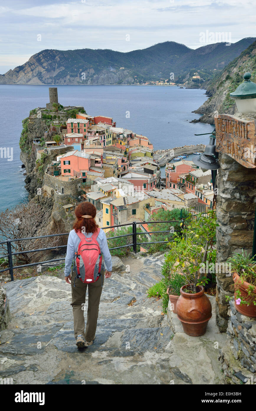 Woman walking on a path towards Vernazza, Mediterranean sea in the background, Vernazza, Cinque Terre, National Park Cinque Terr Stock Photo