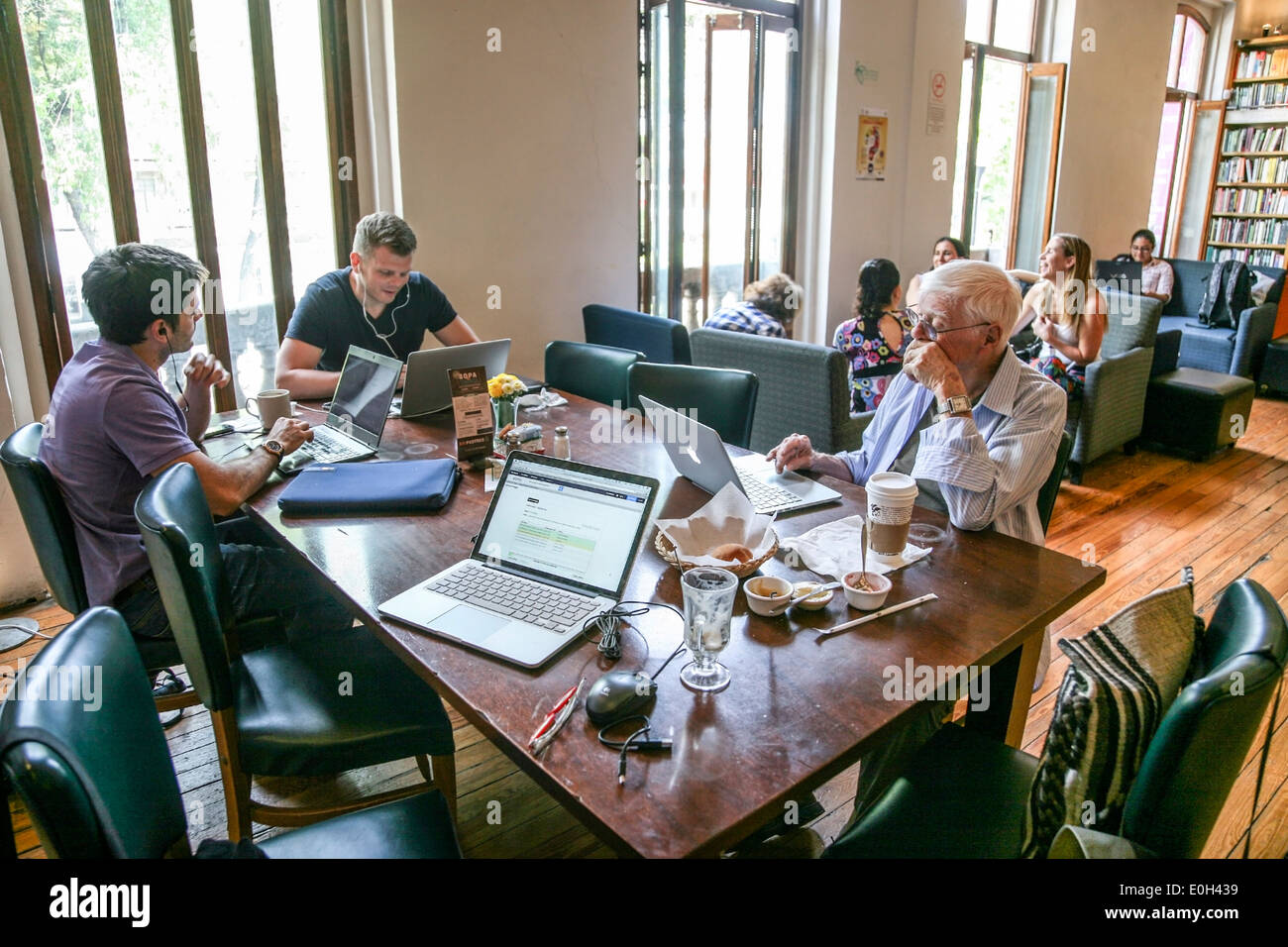 people working at their computers & enjoying breakfast at Cafebreria a combination bookstore restaurant in Roma District Mexico Stock Photo