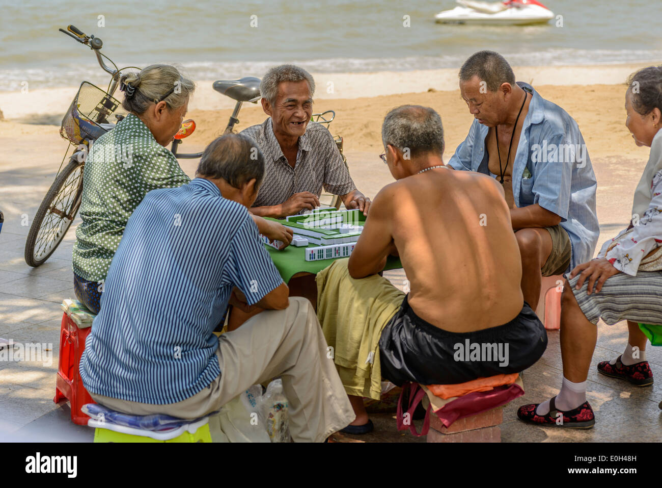 Some old people playing mahjong on the summer beach. Stock Photo