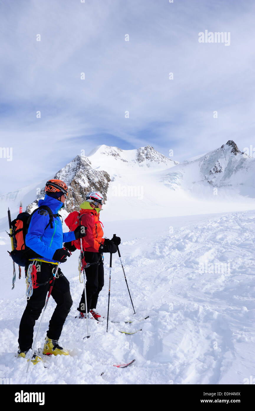 Young woman and young man downhill skiing from Wildspitze on glacier, Oetztal Alps, Tyrol, Austria Stock Photo