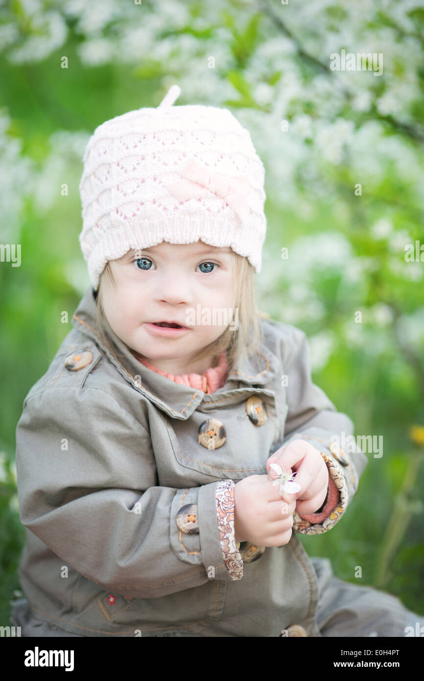 funny girl with Down syndrome in the mouth pulls dandelions Stock Photo