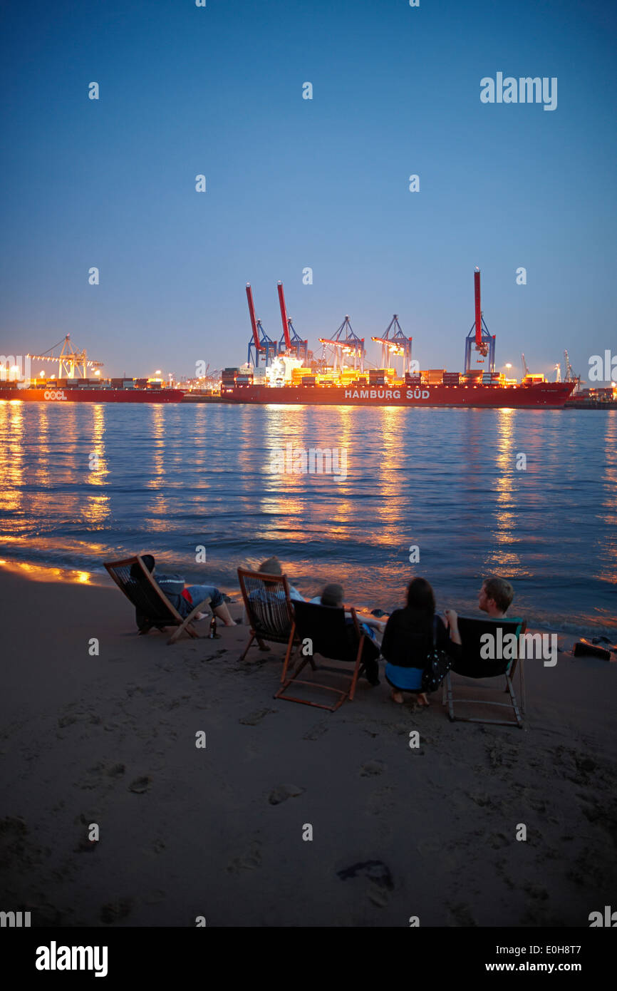 Guests on the beach near Cafe Strandperle in Hamburg-Oevelgoenne, the HHLA container terminal is situated on the opposite bank o Stock Photo