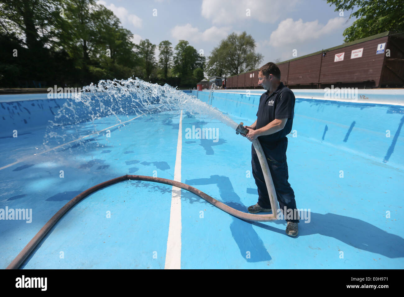 A man filling an outdoor swimming pool with a hose Stock Photo Alamy