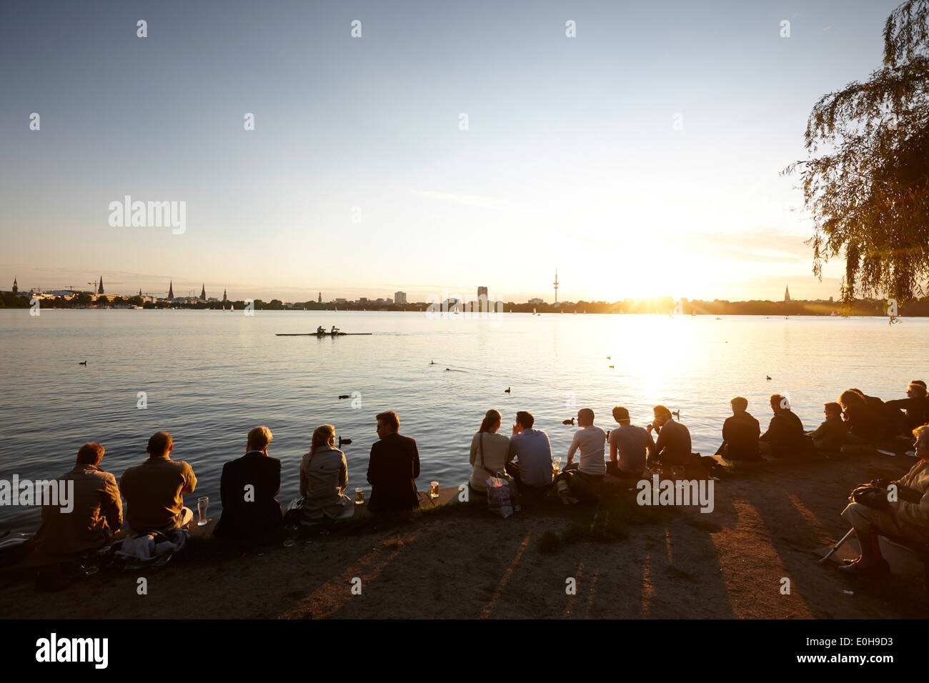 People sitting on seawall at Alsterperle cafe and bar, Eduard-Rhein-Ufer 1, Outer Alster Lake, Hamburg, Germany Stock Photo