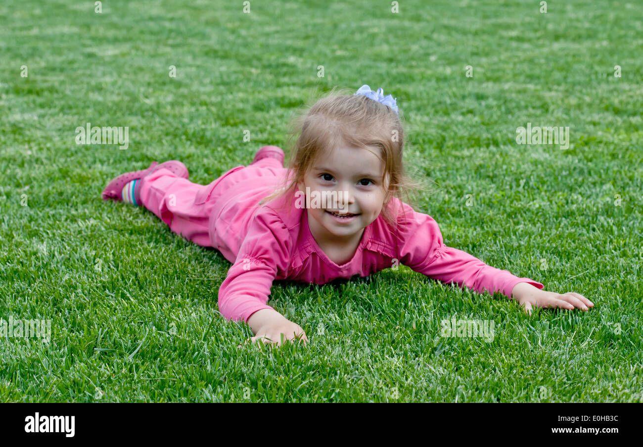 Portrait of a smiling little girl, lying on green grass Stock Photo - Alamy