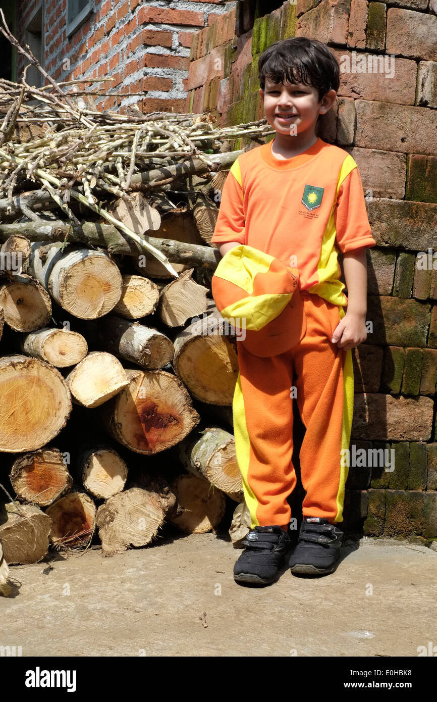 Boy East Java young local boy in school uniform standing by a wood pile in a rural ...