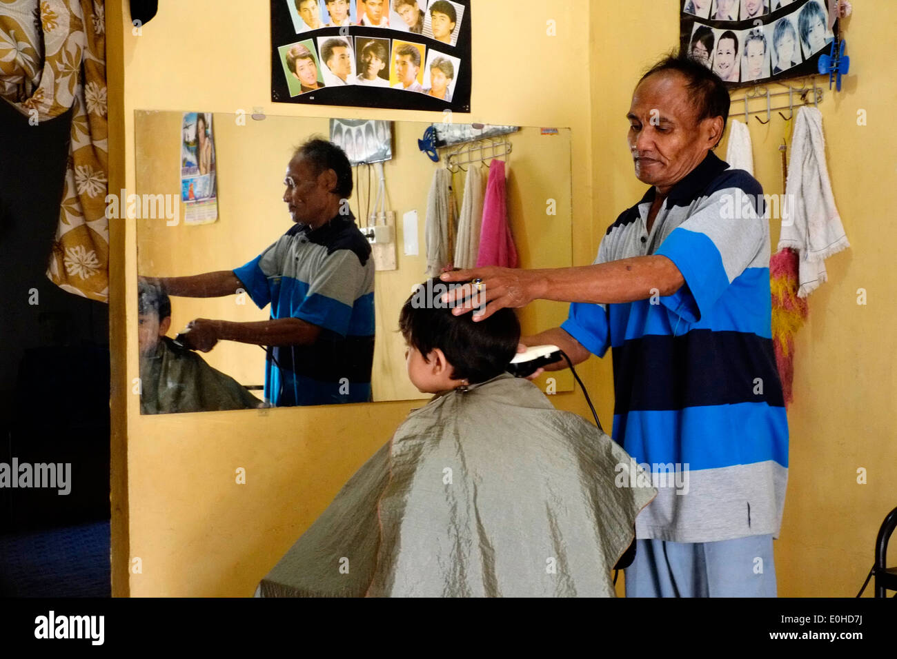 little boy having a haircut in a small village home salon in east java indonesia Stock Photo