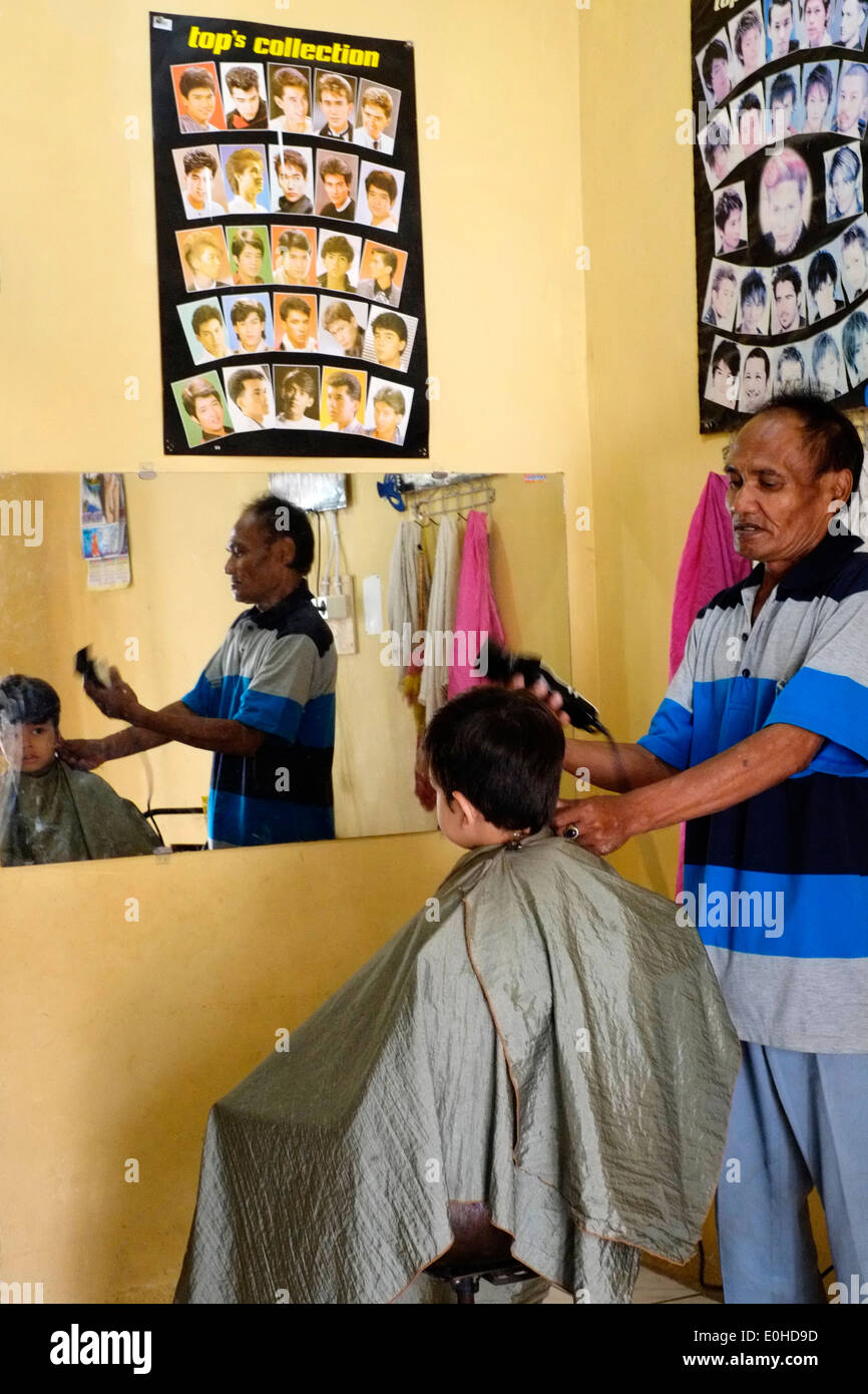 little boy having a haircut in a small village home salon in east java indonesia Stock Photo