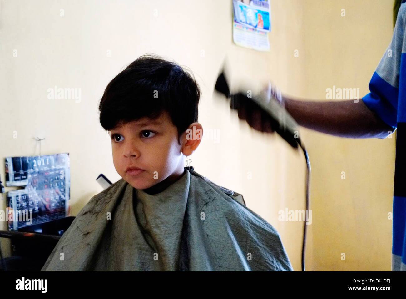 little boy having a haircut in a small village home salon in east java indonesia Stock Photo