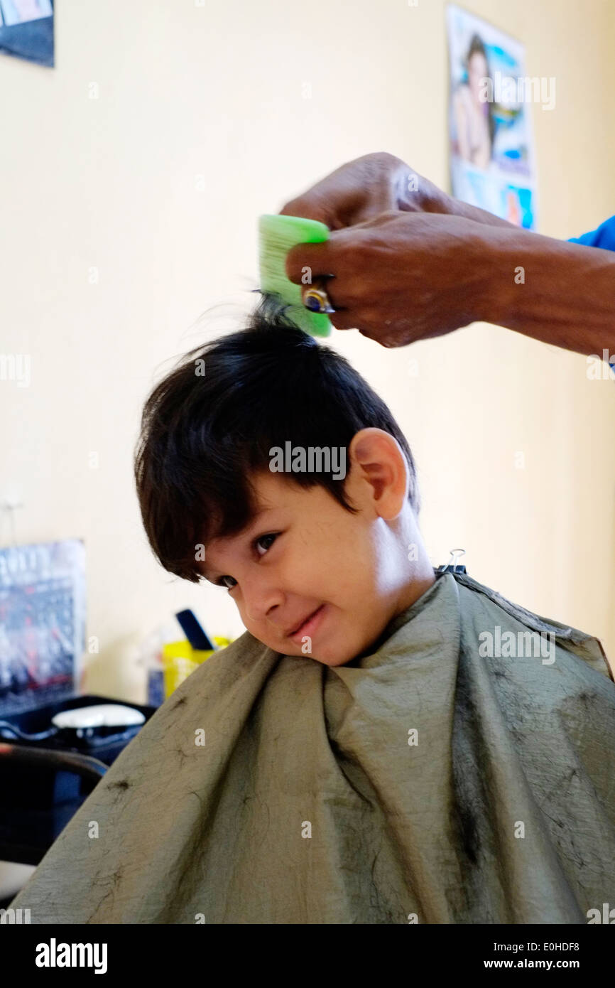 little boy having a haircut in a small village home salon in east java indonesia Stock Photo