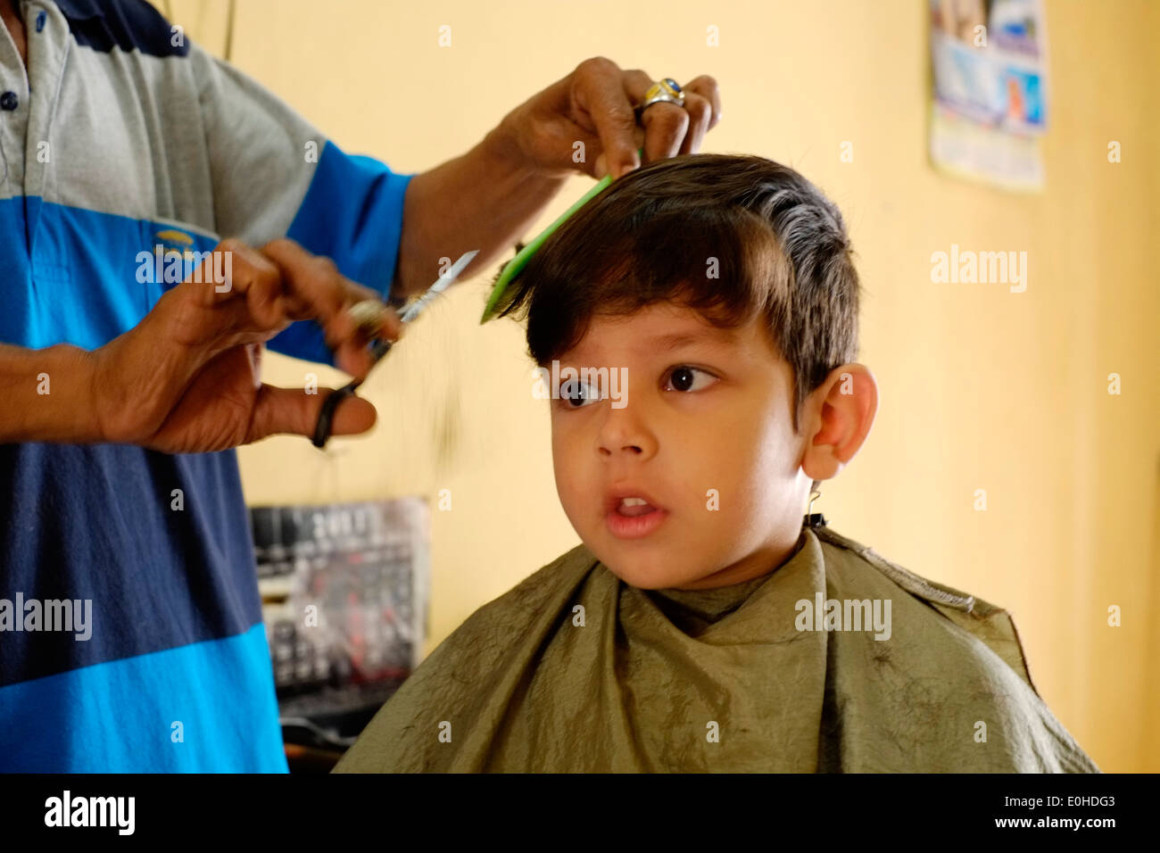 little boy having a haircut in a small village home salon in east java indonesia Stock Photo