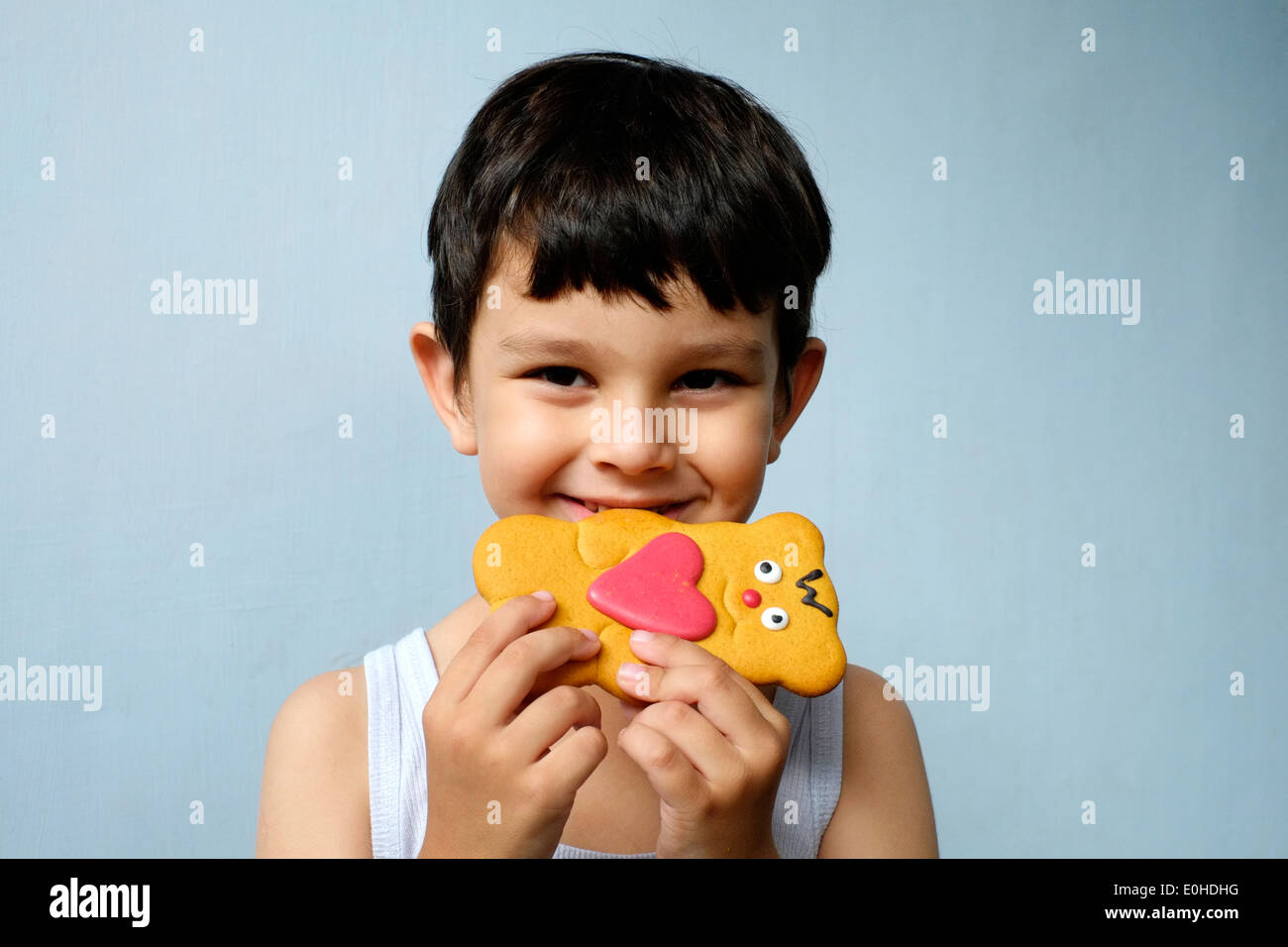 smiling happy little boy eating a decorated gingerbread man Stock Photo