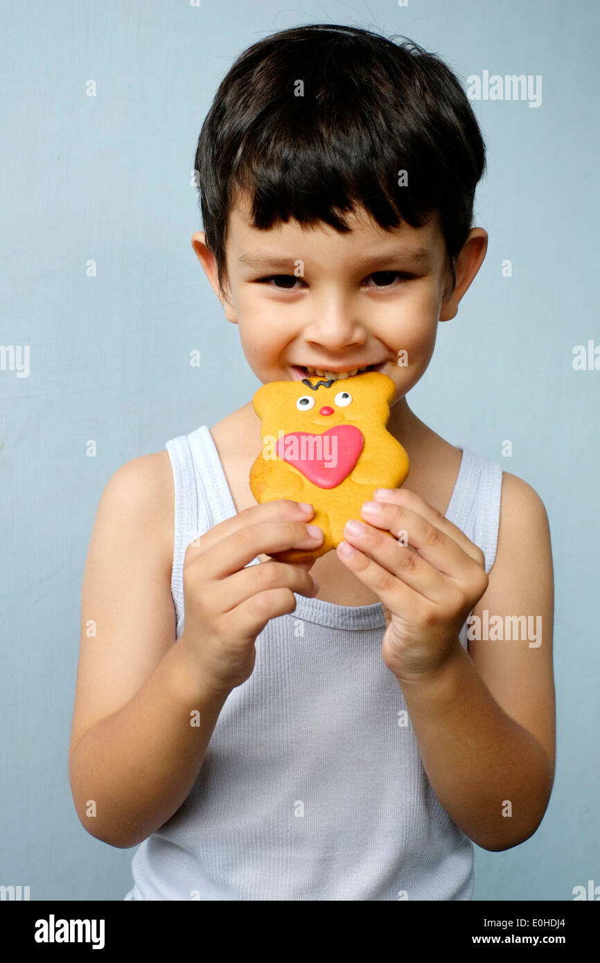 smiling happy little boy eating a decorated gingerbread man Stock Photo
