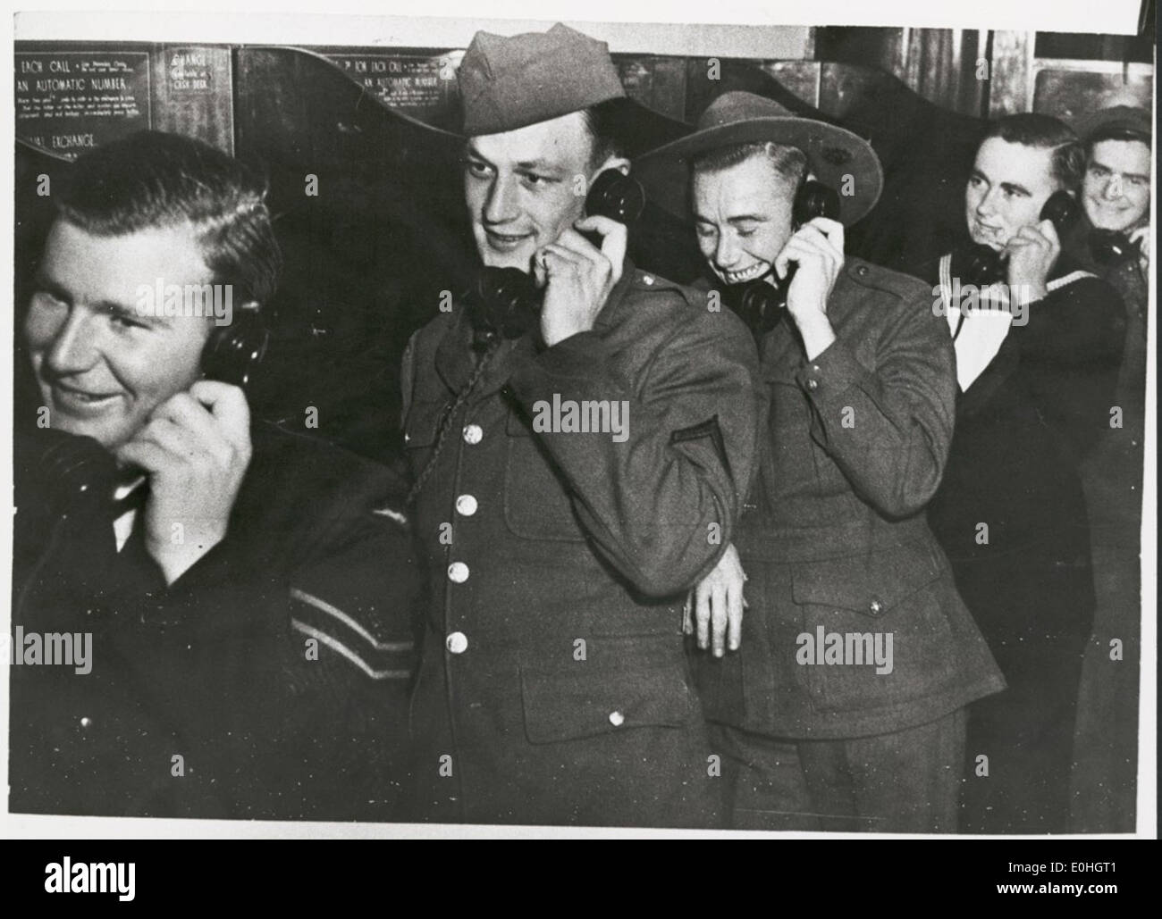 Servicemen in the Royal Australian Air Force, United States Army, Australian Imperial Force and Royal Australian Navy chatting to their girlfriends on the telephone, Melbourne, 1942. Stock Photo