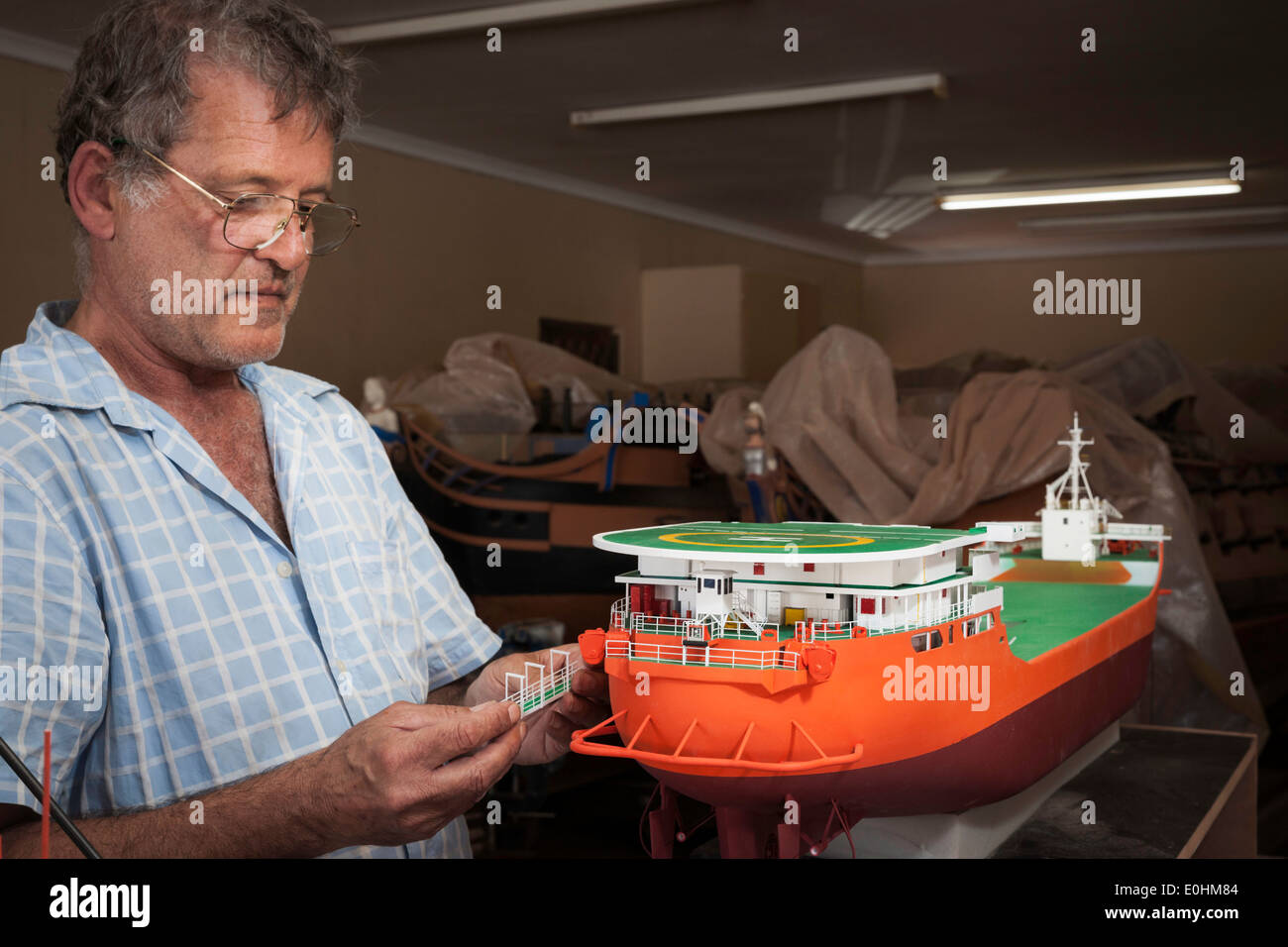 Man holds a miniature railing that will decorate the handcrafted model of the DeBeers Diamond Mining ship Stock Photo
