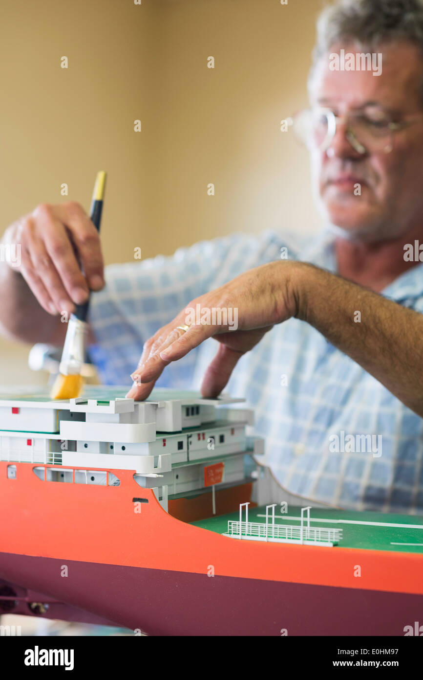 Man brushes dust from a model of the DeBeers Diamond Mining ship operating off the coast of Namibia, Model Ship Builder, ShipYar Stock Photo
