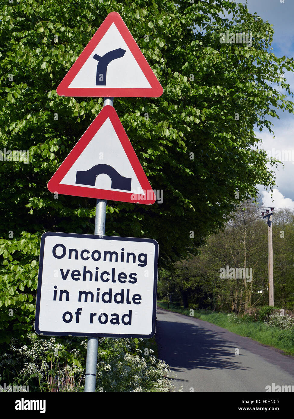 Road narrows sign Oncoming vehicles in middle of road in Cheshire UK Stock Photo