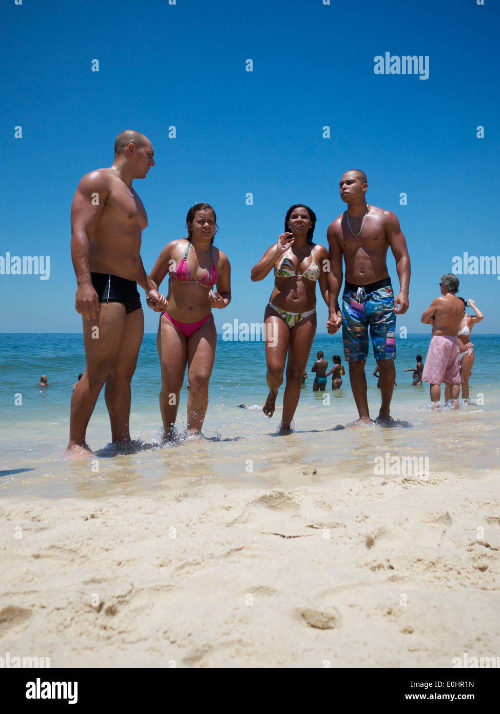 RIO DE JANEIRO, BRAZIL - JANUARY 22, 2014: Group of Brazilian friends stand along the shore on a summer day on Ipanema Beach. Stock Photo