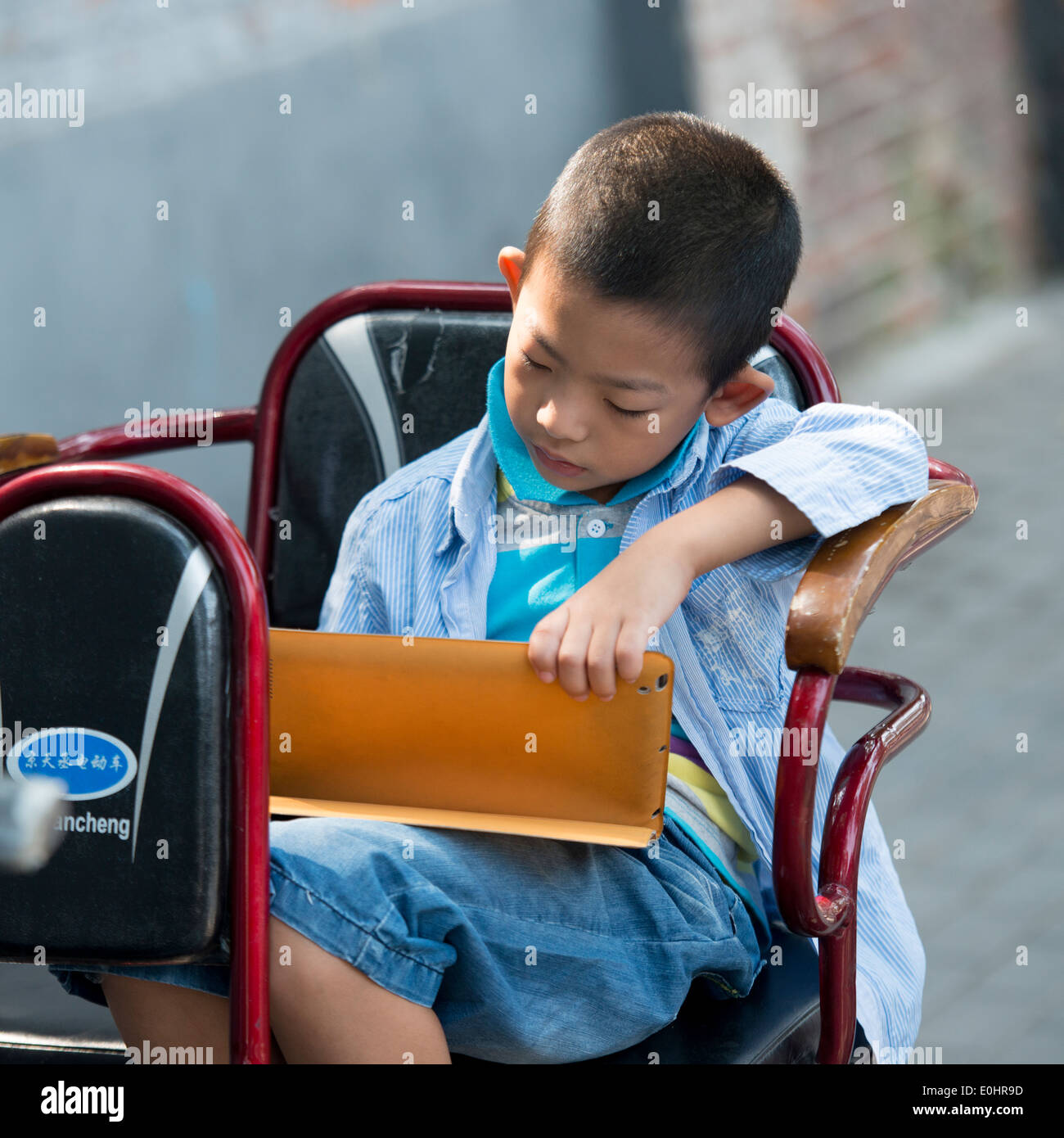 Boy using a digital tablet on cycle rickshaw, Hutong, Xicheng District, Beijing, China Stock Photo