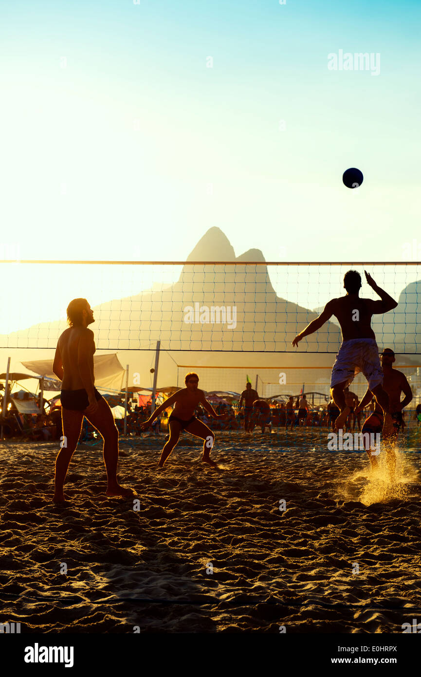 Carioca Brazilians Rio de Janeiro Brazil sunset beach volleyball game against a silhouette of Dois Irmaos Mountain Ipanema Beach Stock Photo