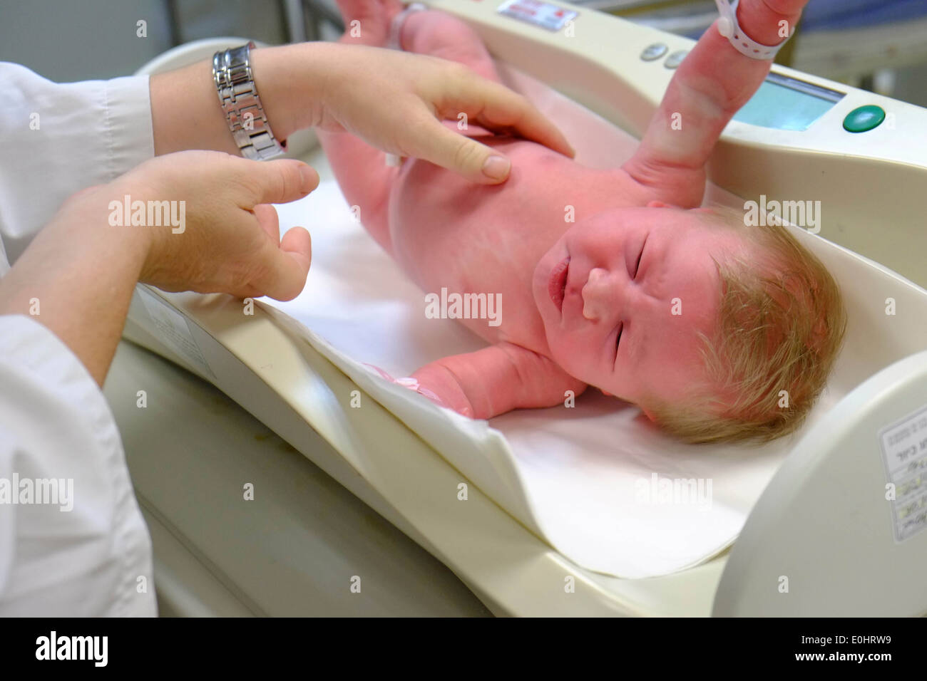 A crying baby girl is being weighed at the hospital after birth Stock