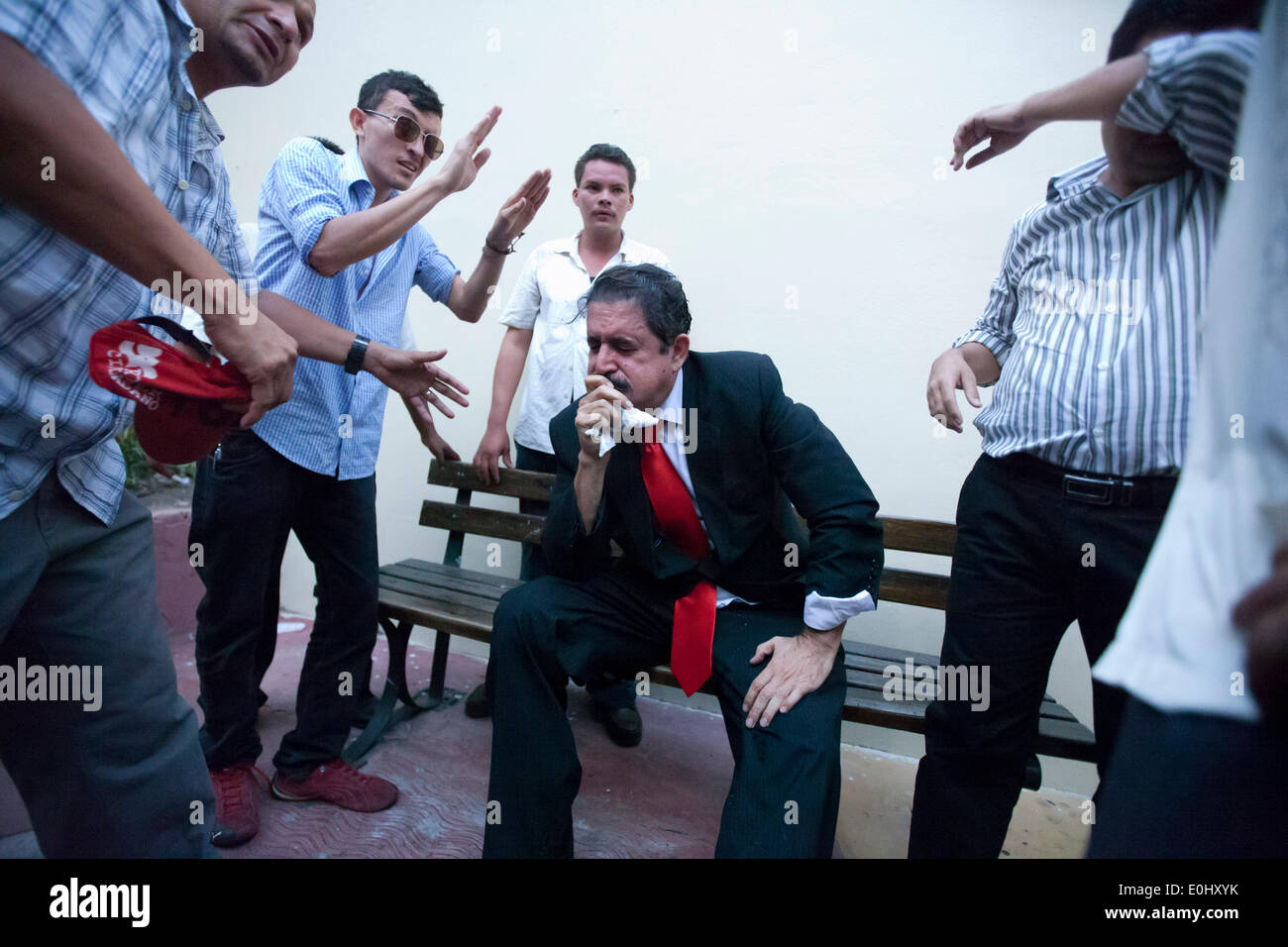 Tegucigalpa, Honduras. 13th May, 2014. The former Honduran President Manuel Zelaya (C) covers his face from tear gas, after being evacuated with his followers from the National Congress, in Tegucigalpa, Honduras, on May 13, 2014. Followers and deputies of the Liberty and Refoundation Party (Libre, for its acronym in Spanish), the second political force in Honduras, broke in the National Congress on Tuesday, after clashing with police elements that guarded the Legislative Palace. Credit: Rafael Ochoa/Xinhua/Alamy Live News Stock Photo