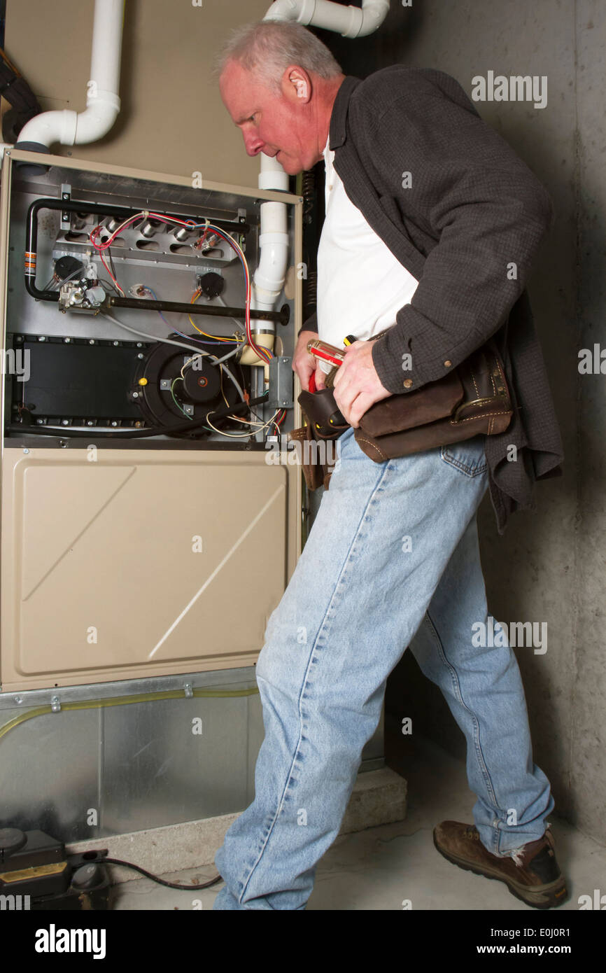 Repairman servicing or repairing basement furnace unit Stock Photo
