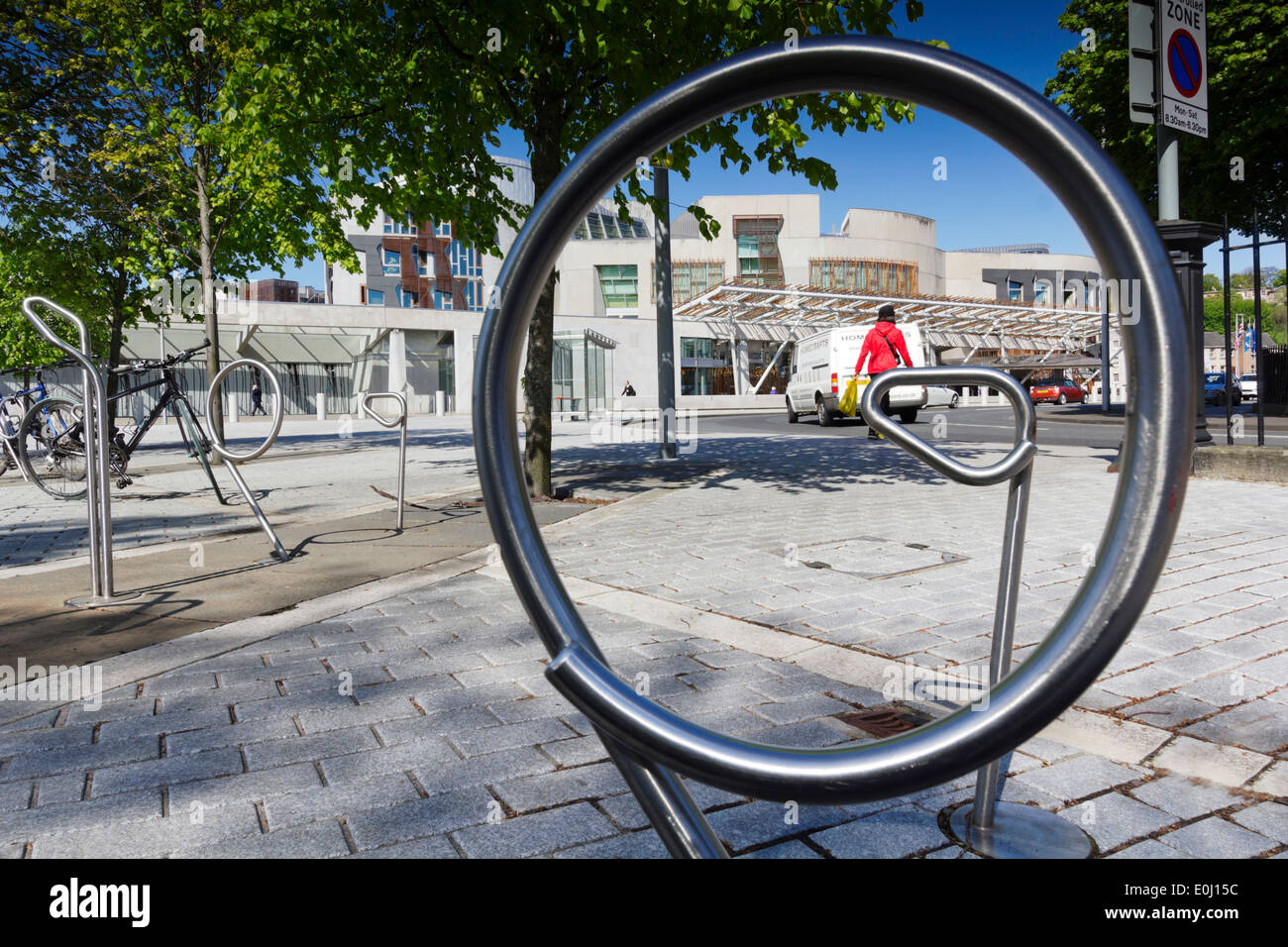 Scottish Parliament Building Through Circle Of Bike Rack. Blue Sky And Green Foliage On Trees Stock Photo