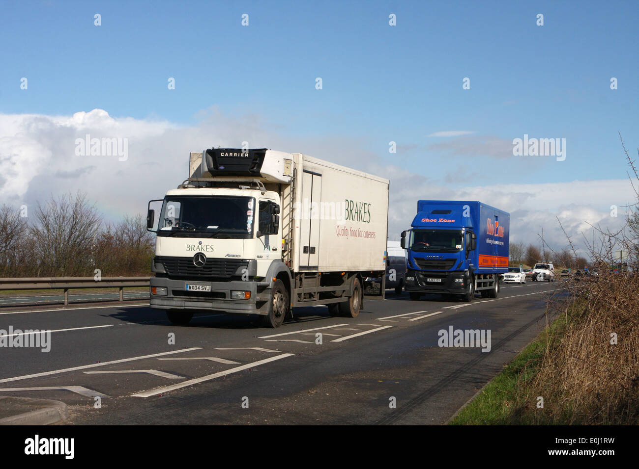 Two trucks and cars traveling along the A46 dual carriageway in Leicestershire, England Stock Photo