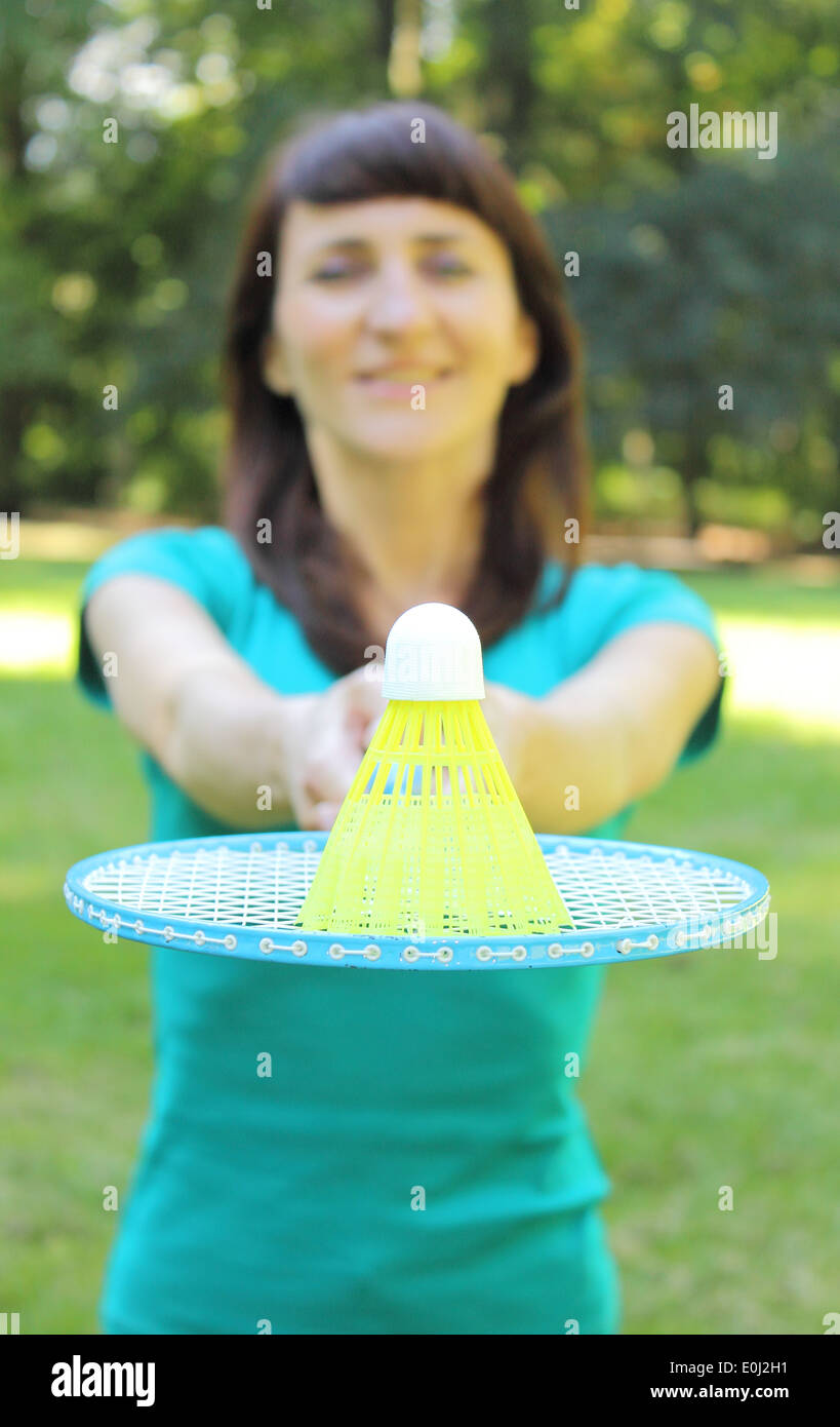 Smiling woman in the summer park with badminton racket and badminton shuttlecock with plastic