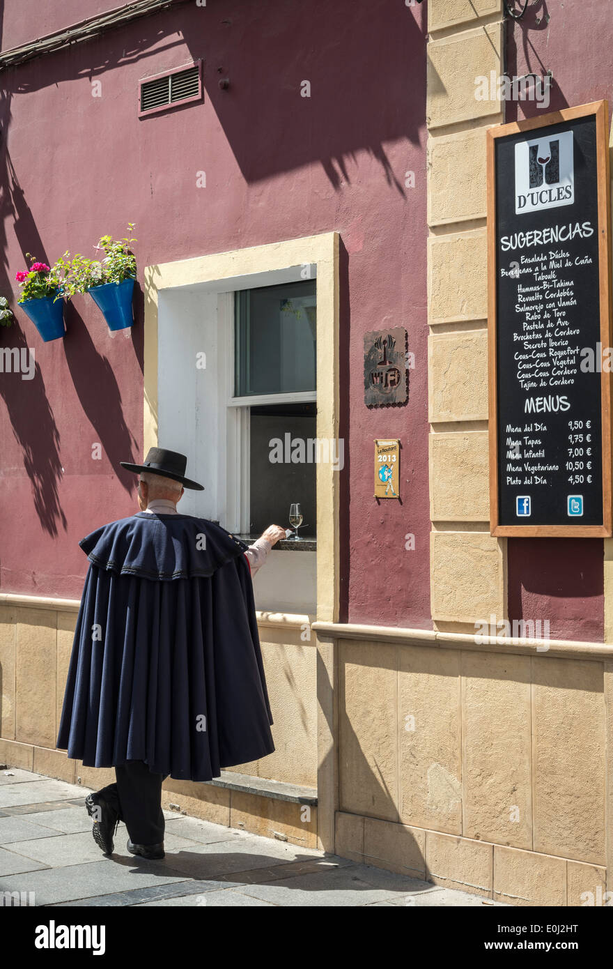 A man in a traditional Andalucian hat and cloak stops for a drink at a bar near the Plaza del Potro Cordoba, Andalucia, Spain. Stock Photo