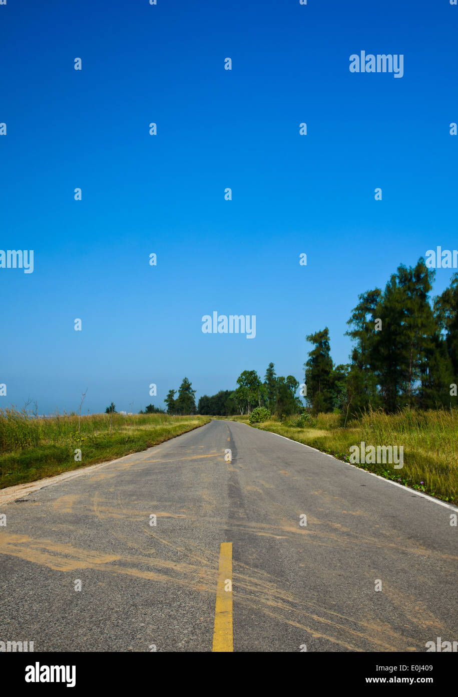 Long road stretching out into the distance under a dramatic blue sky Stock Photo