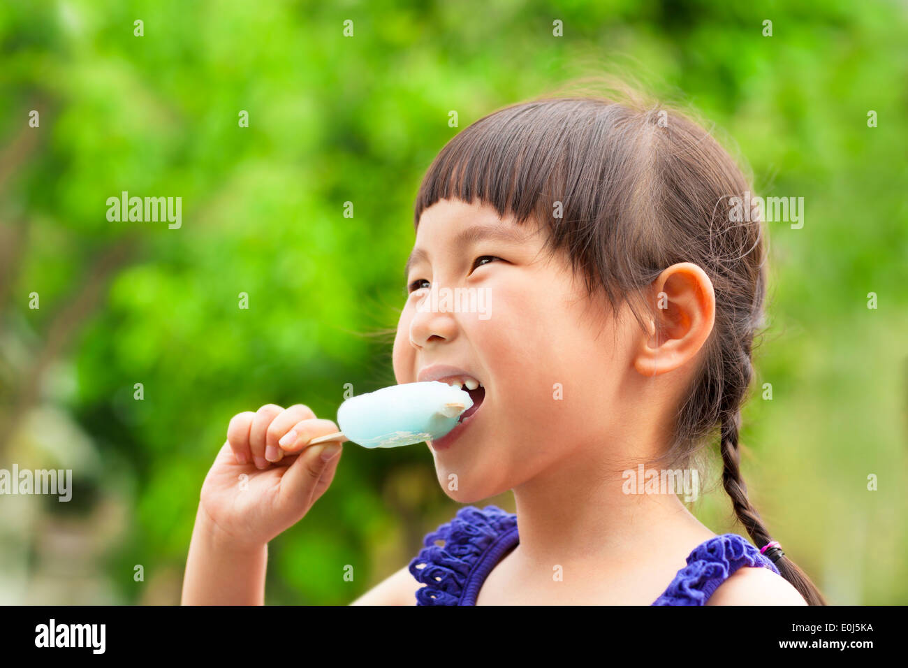 happy little girl eating popsicle at summertime Stock Photo