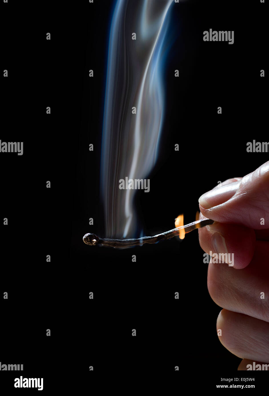 Match burning with the flame almost burning the fingers. Stock Photo