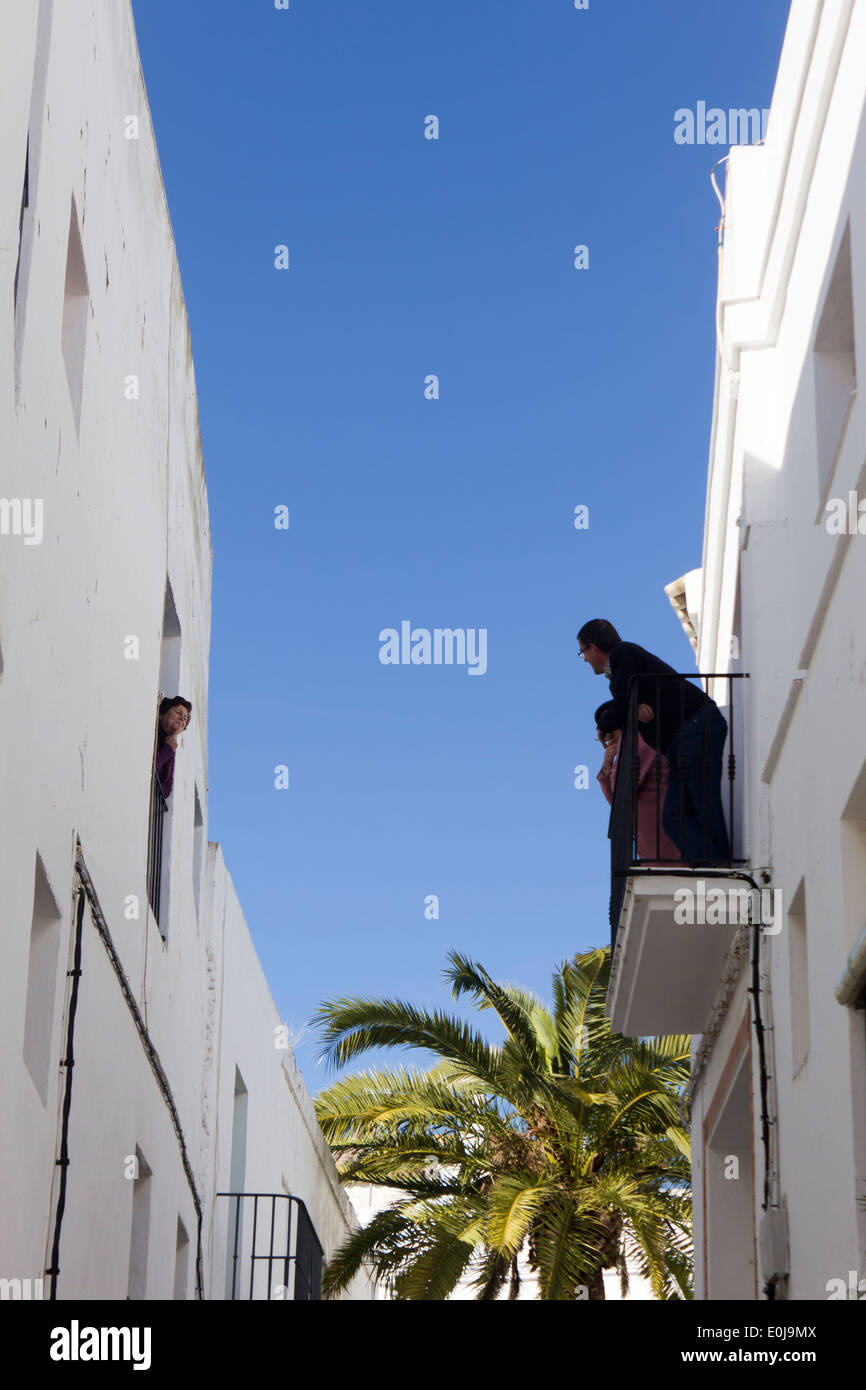 Vejer de la Frontera, Cadiz Province, Andalusia, Spain. Neighbours chatting from house to house in one of the narrow streets. Stock Photo