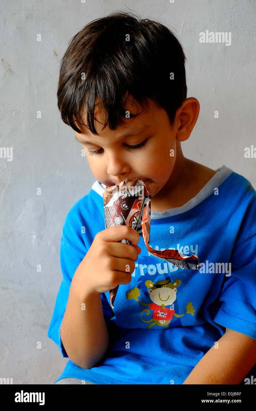 young boy eating a chocolate ice cream and getting most of it smeared over his face Stock Photo