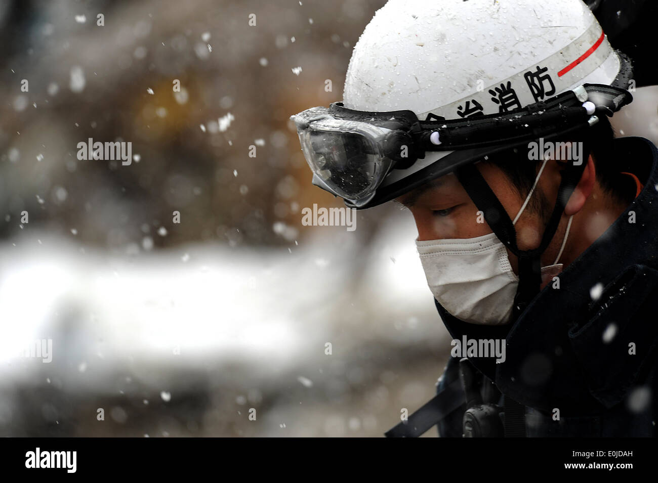 A member with the Japanese Search and Rescue team searches through the damage and debris on March 17, 2011, in Unosumai, Japan Stock Photo