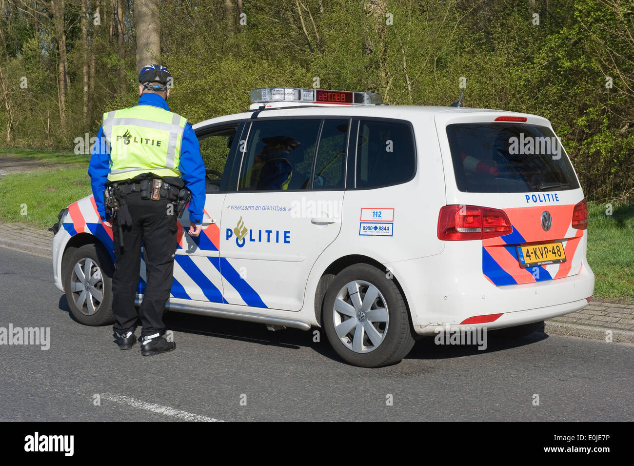 A policeman is taking to a colleague in a police car during a surveillance on the street Stock Photo